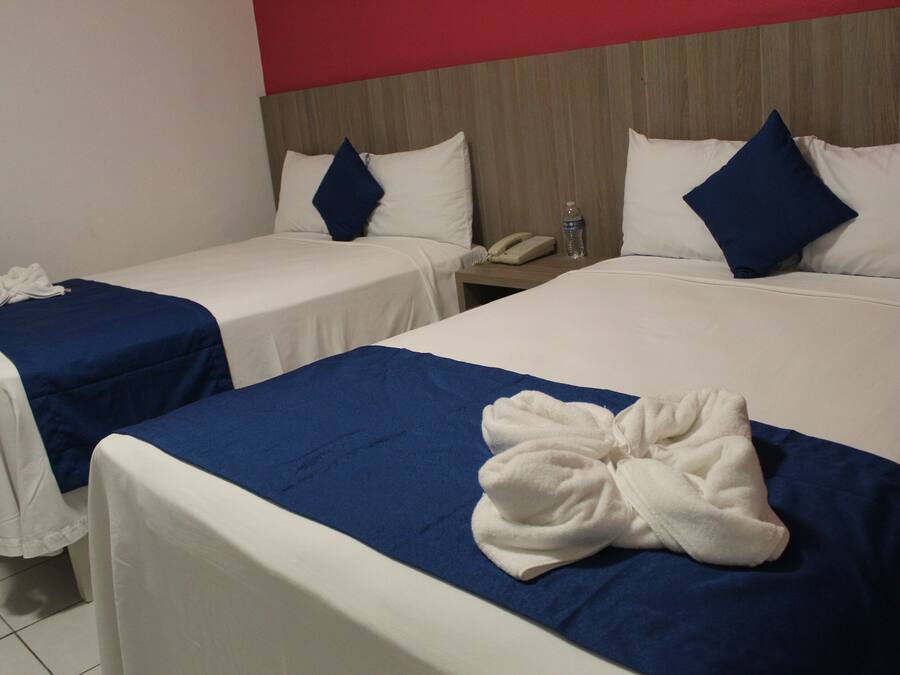 A hotel room with two single beds, each with a blue bedspread and white linens. There is a white bathrobe on the bed in the foreground.