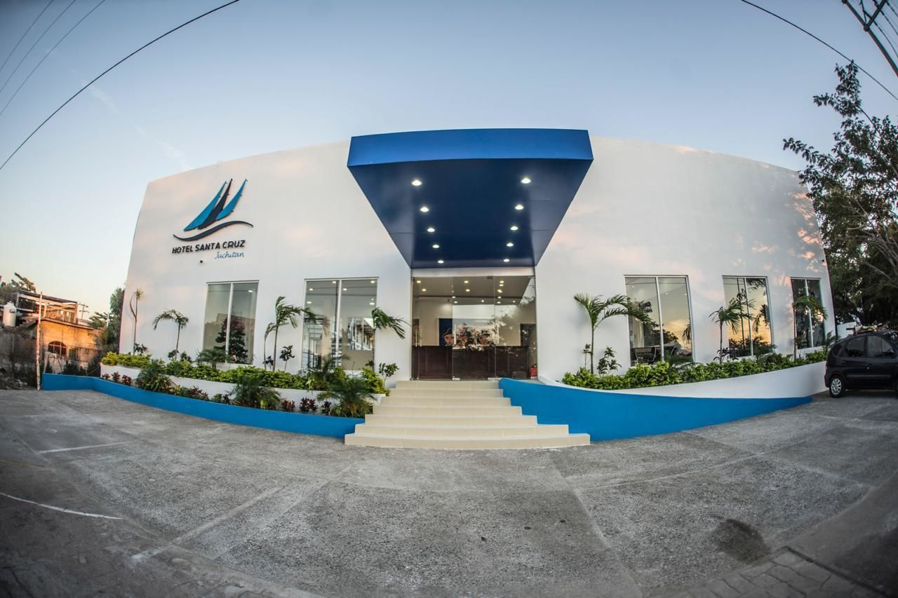 A modern hotel with a blue and white facade, a prominent entrance with steps, and a landscaped area with plants.