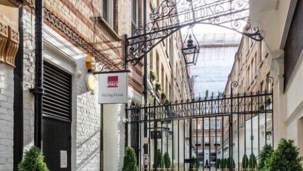 A gated entrance to a building with a brick facade, a sign indicating a spa, and potted plants along the pathway. - Roomspace Apartments -Sterling House (London)