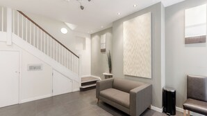 A modern interior with a staircase, a sofa, a chair, and a small table. - Roomspace Apartments -Sterling House (London)