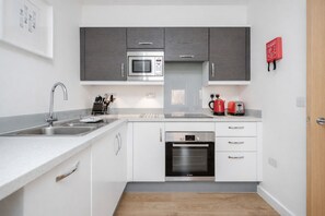 A modern kitchen with a built-in microwave, oven, and toaster. - Roomspace Apartments -Swan House (Leatherhead)
