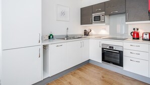 A modern kitchen with white and grey cabinets, a Bosch oven, and a red coffee maker. - Roomspace Apartments -Swan House (Leatherhead)