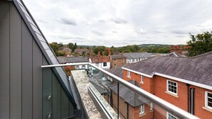 A residential area with houses, a balcony, and a cloudy sky. - Roomspace Apartments -Swan House (Leatherhead)