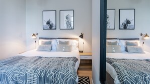 A modern hotel room with two beds, a wooden nightstand, and wall-mounted lamps. - Californication (Southend-on-Sea)