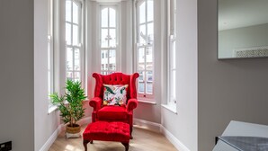 A corner room with a red upholstered chair, a potted plant, and large windows. - Californication (Southend-on-Sea)