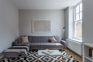 Un salon moderne avec un canapé gris, un tapis à motifs et un livre posé sur une table basse.