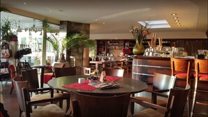 Un restaurant avec des tables rondes, des chaises et un coin bar.