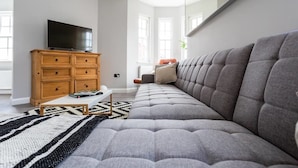 A modern living room with a grey sofa, wooden cabinet, and a flat-screen TV. - Exhale (Southend-on-Sea)