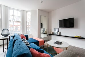 Relax in this stylish living room with a large window, flat-screen TV, and comfortable sofa.