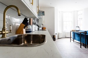 Enjoy cooking in this well-equipped kitchen with a stainless steel sink and brass faucet, complemented by a spacious living area.