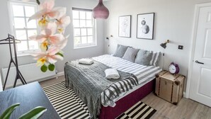 Une chambre à coucher avec un lit, un radiateur, une fenêtre, une table de chevet, une lampe et une valise.