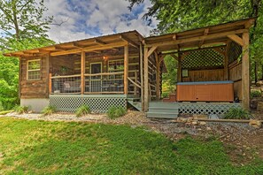 Ein rustikales Blockhaus mit überdachter Veranda, Whirlpool und einem umzäunten Bereich.