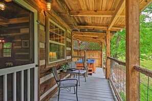Une terrasse en bois avec une table et des chaises, un jacuzzi et une vue sur la verdure environnante.