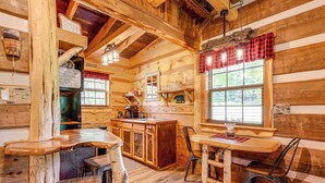 A rustic cabin interior with a wooden bar, dining table, and chairs. - Covered Deck & Fire Pit: Smoky Mountain Cabin (Cosby)