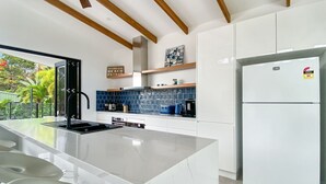Eine moderne Küche mit einer großen Kücheninsel, weißen Schränken und einem integrierten Kühlschrank.