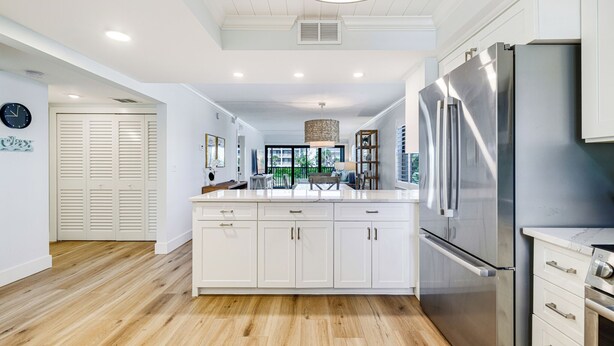 Une cuisine moderne avec des meubles blancs, des appareils électroménagers en acier inoxydable et un plancher en bois.
