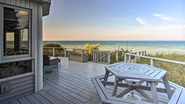 A wooden deck with a table and chairs, overlooking a beach. - Lakefront Montague Cottage w/ Deck & Beach! (Montague)