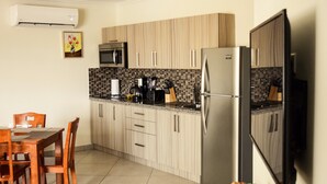 A compact kitchen with wooden cabinets, a microwave, a coffee maker, and a refrigerator. - Bright Condo steps to Eagle Beach (Oranjestad-West)