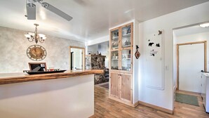 A kitchen with a wooden countertop, a stone backsplash, and a chandelier. There is a cabinet with glass doors and a refrigerator. - Walk to Lake: Rustic Home w/ Deck in Fawnskin (Fawnskin)