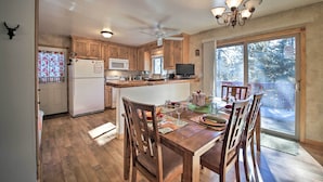 A spacious kitchen with wooden cabinets, a central island, and a dining area with chairs and a table. - Walk to Lake: Rustic Home w/ Deck in Fawnskin (Fawnskin)