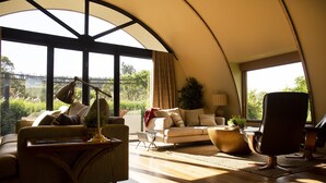 A spacious living room with a large window, a sofa, a coffee table, and a chair. - Glenlowren - A magical haven in the Yarra Valley (Dixons Creek)