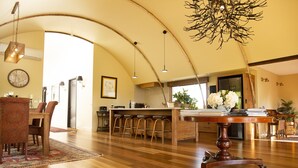 A spacious kitchen with wooden flooring, a central island with bar stools, and pendant lighting. - Glenlowren - A magical haven in the Yarra Valley (Dixons Creek)