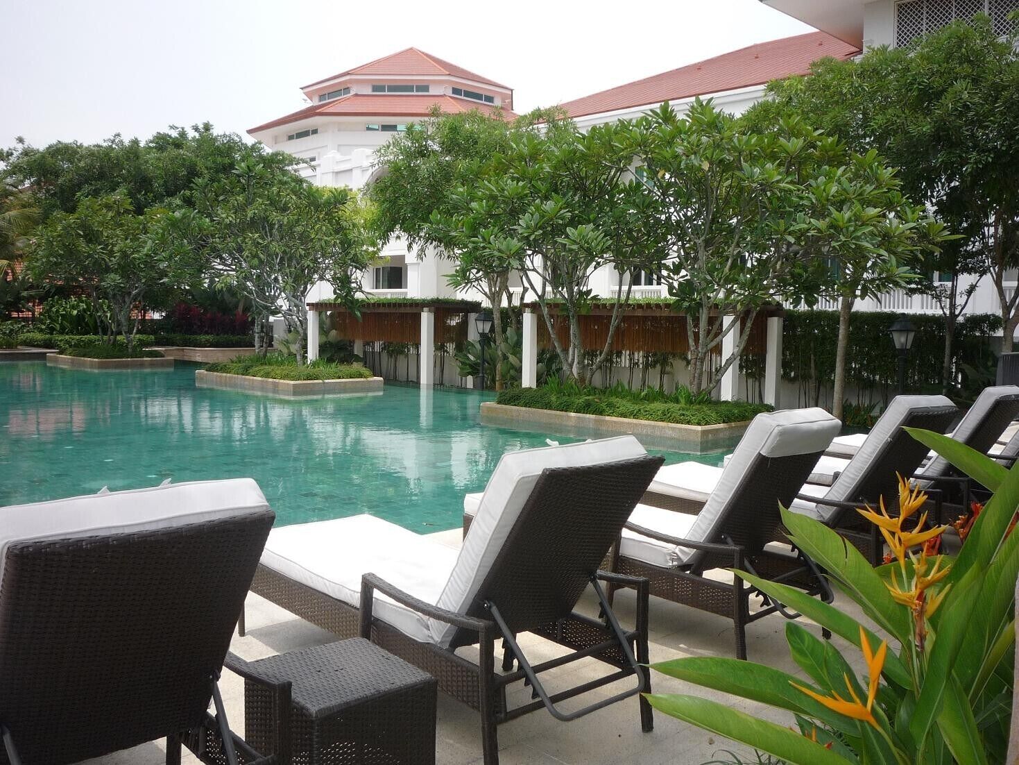 A swimming pool with lounge chairs and a building in the background.