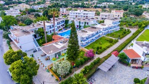 A residential area with modern buildings, a swimming pool, and well-maintained gardens. - Yannis Yard Studios And Apartments (Kos)