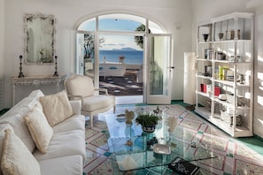 A living room with a white sofa, a glass coffee table, and a white bookshelf. - Apollon Club (Serrara Fontana)