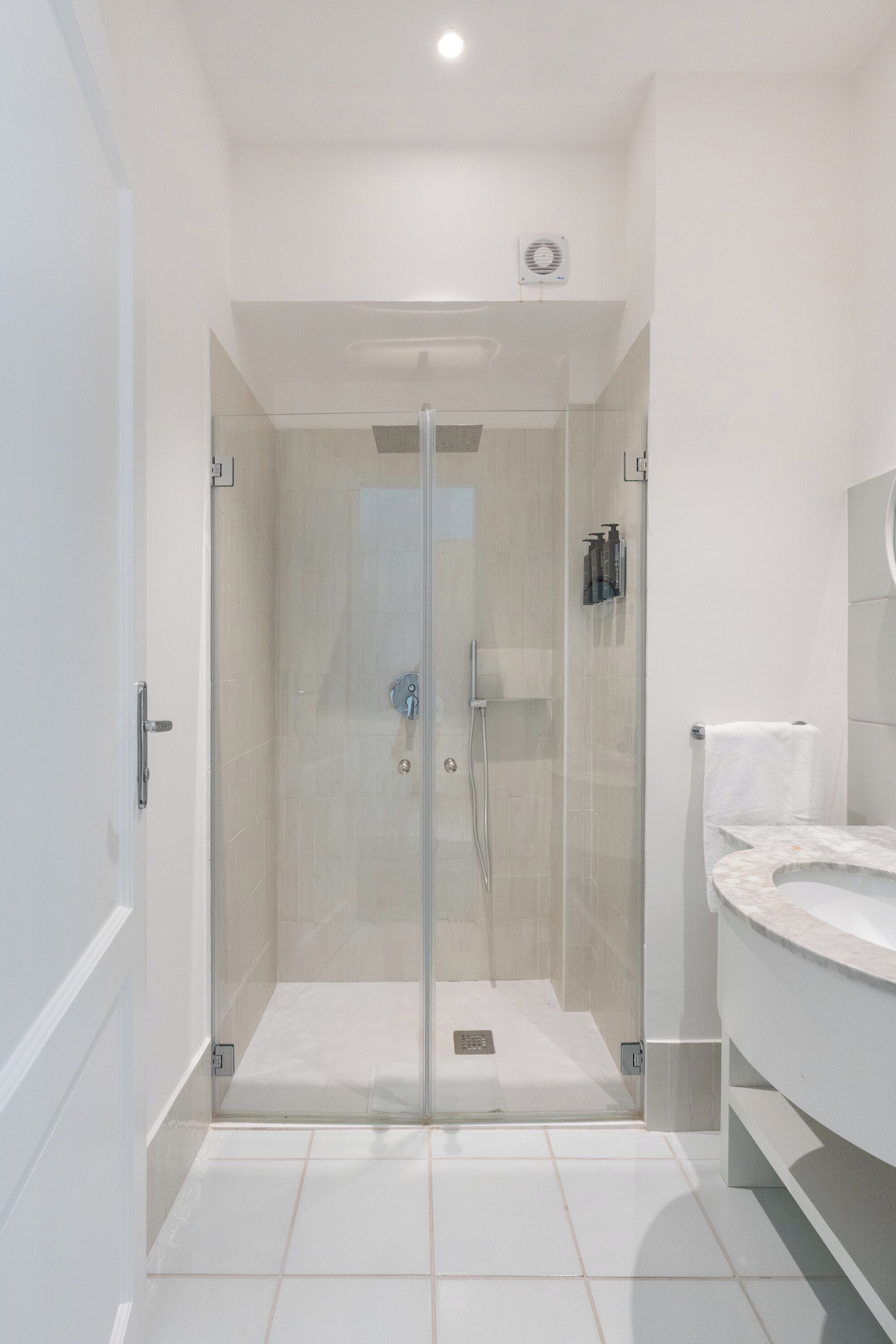 Un baño moderno con ducha de vidrio, un lavamanos blanco y un inodoro.