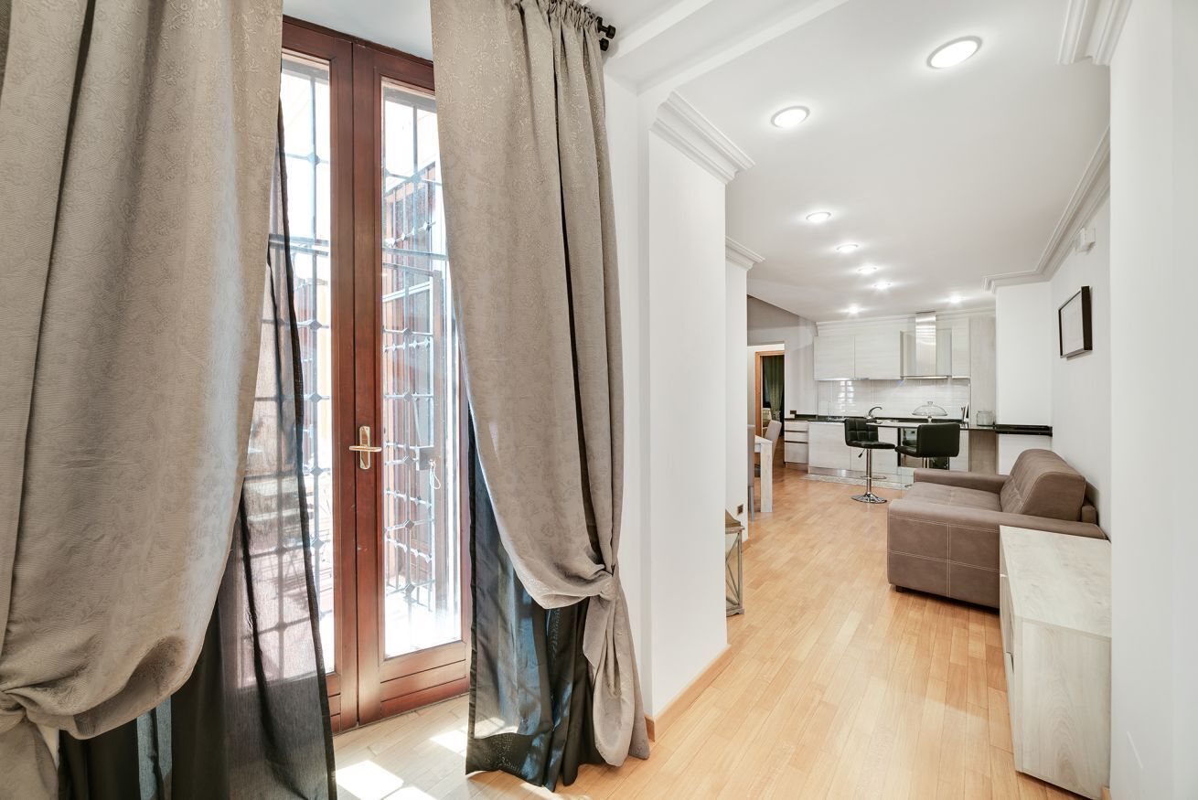 A modern apartment with a living area, kitchenette, and a balcony with a view.