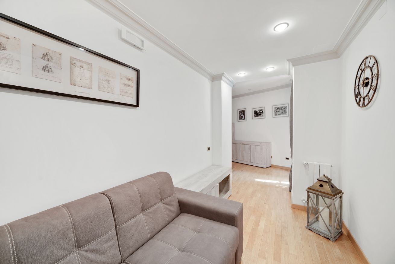 En moderne stue med sofa, billeder på væggen og en dekorativ lanterne.