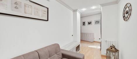 En moderne stue med sofa, billeder på væggen og en dekorativ lanterne.