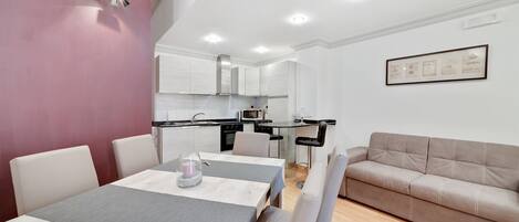 A modern apartment with a dining area, kitchenette, and a living space.