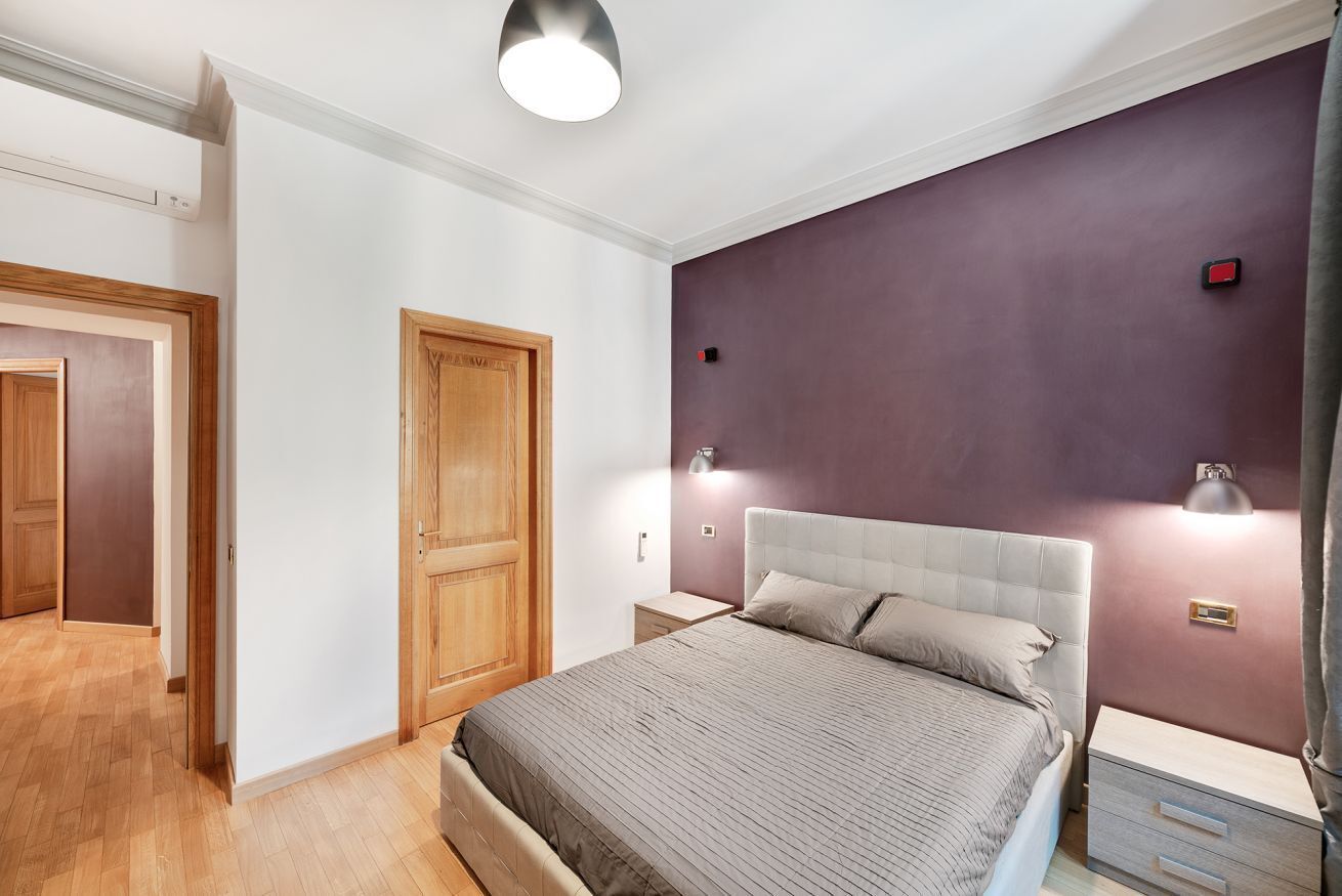 A bedroom with a bed, bedside tables, and a wardrobe.