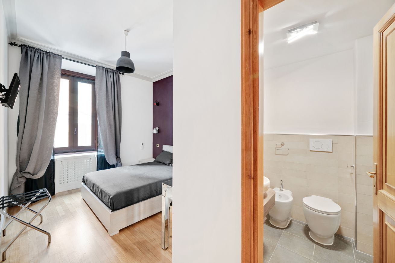 Ein modernes Schlafzimmer mit Bett, Heizkörper und einem Vorhangfenster.