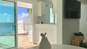 A modern interior with a white table, a vase, a kitchen area, and a balcony with a view of the sea. - Casa Atlantica - beautiful Seaview Apartment (Las Playitas)