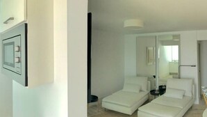 A modern, minimalist bedroom with two white sofas, a bedside table, and a mirror. - Casa Atlantica - beautiful Seaview Apartment (Las Playitas)