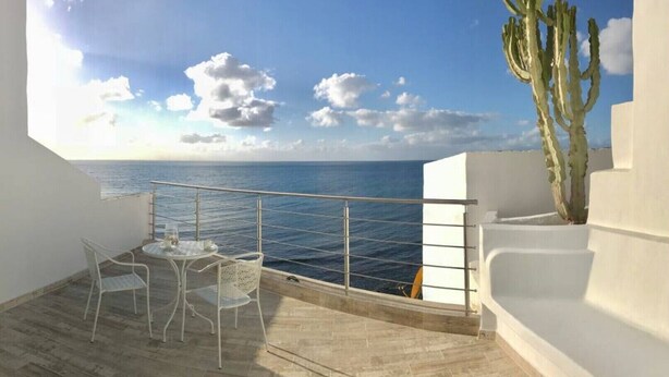 A balcony with a view of the sea, a cactus, and a white chair and table. - Casa Atlantica - beautiful Seaview Apartment (Las Playitas)