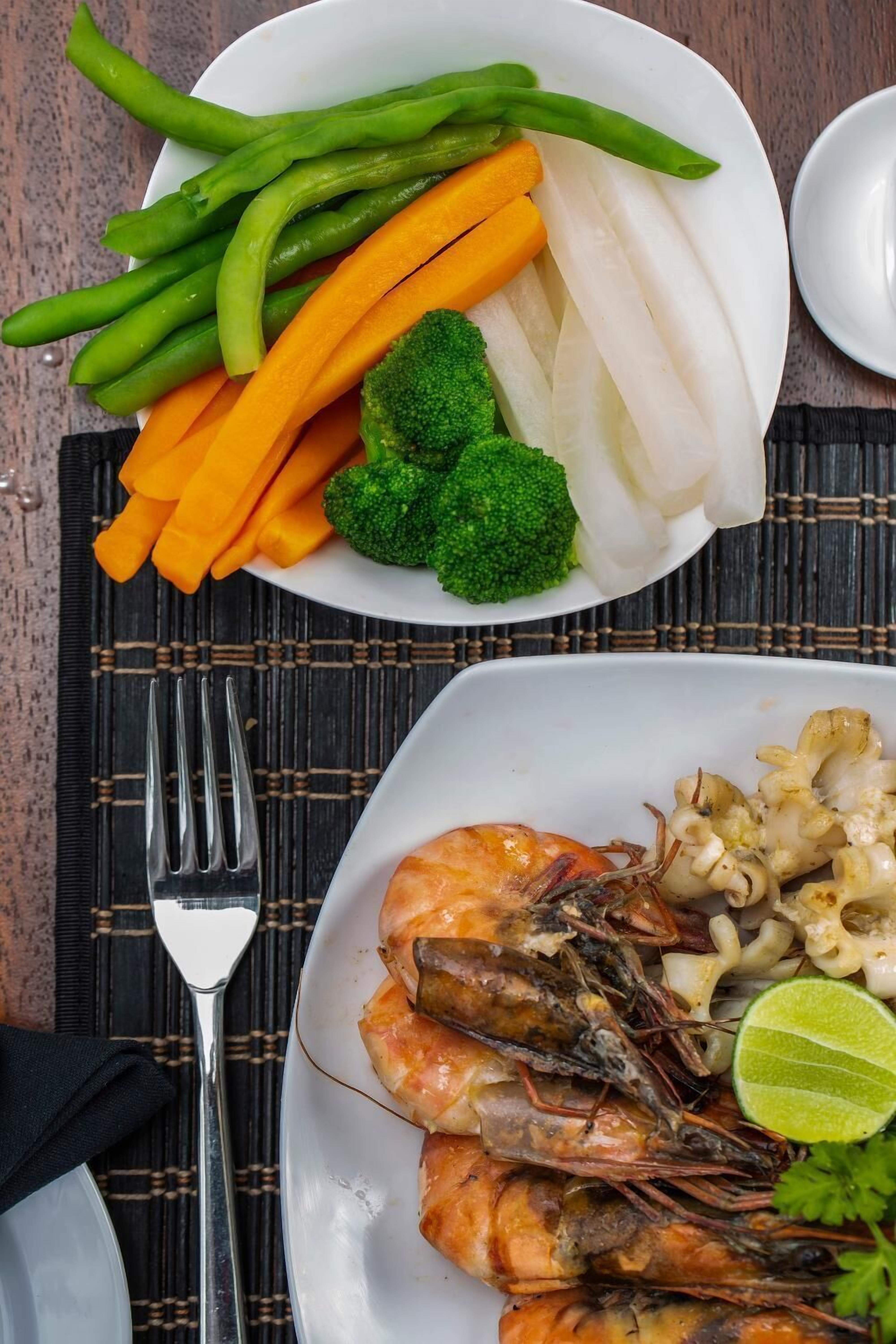 A plate of shrimp with vegetables and a lime wedge.