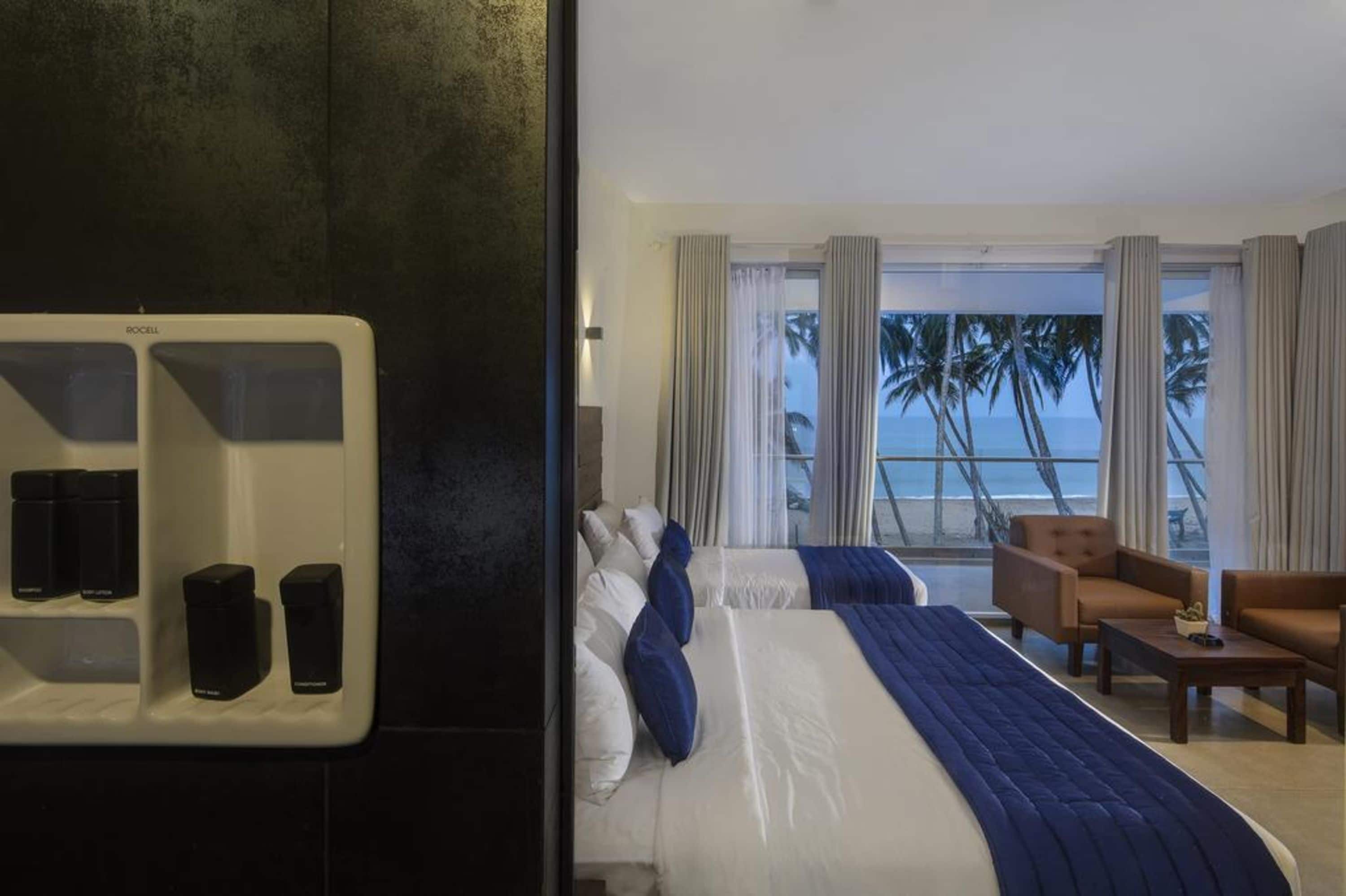 A hotel room with a bed, two chairs, a coffee table, and a view of the ocean.