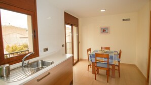 A kitchen with a sink, wooden cabinets, a window, and a dining area with a table and chairs.