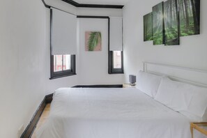 Relax in a serene bedroom with a large bed, bedside table, and framed picture.