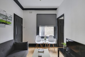 Relax in this stylish living space with a sofa, dining table, and TV stand, offering a comfortable spot to unwind and enjoy the urban view.