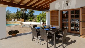 Une terrasse extérieure avec une table et des chaises, une piscine et une vue sur le paysage environnant.