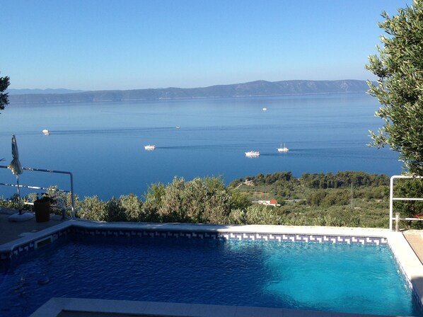 A swimming pool with a view of the sea and boats.