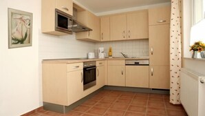 Une cuisine avec des meubles de couleur claire, un four à micro-ondes, une cuisinière et un lave-vaisselle.