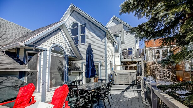 A covered patio with a table and chairs, a deck railing, and a snow-covered tree.