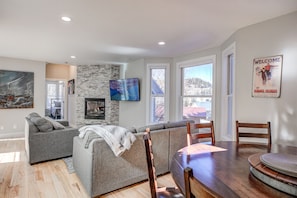 Relax in a cozy seating area with a sofa and accent chair near a large window offering a view of the surrounding landscape.