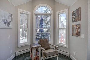 Relax in a cozy corner with a cushioned chair and small table, enjoying views of the outdoors from large windows.